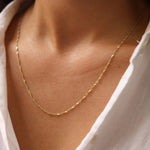 Gold necklace on a person wearing a white shirt