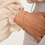 Gold bracelet on a wrist with a light background