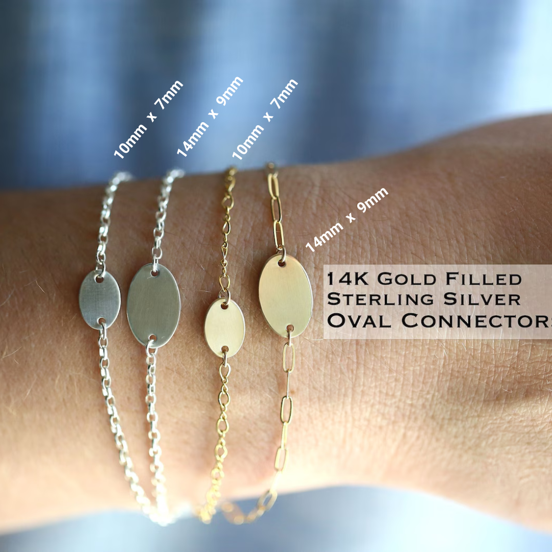 Three bracelets with oval connectors on a wrist, labeled for size and material.