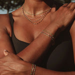 Close-up of a person wearing multiple jewelry necklaces and bracelets. Available in welded permanent or clasped jewelry