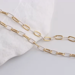 Gold and silver chain necklaces on a light gray background