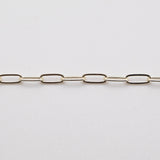 A silver paperclip chain laid out on a white surface.