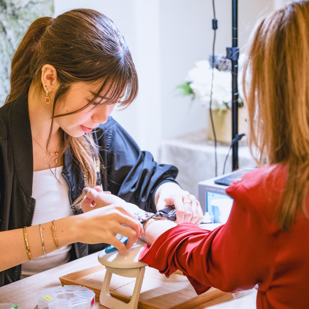 Woman getting permanent jewelry with a focus on the jewelry making process.