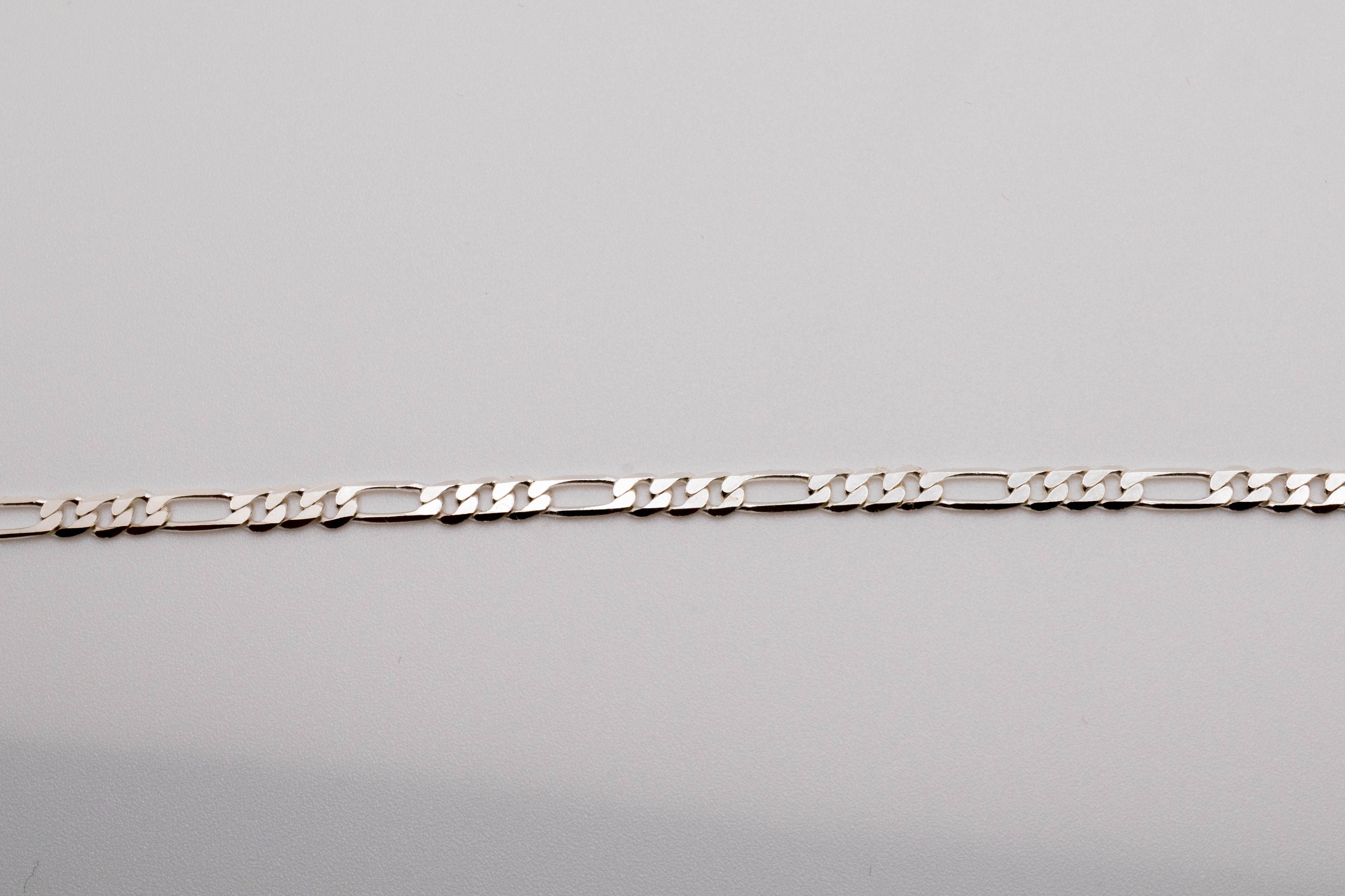 A silver-colored Hermes 925 bracelet laid out on a plain surface.