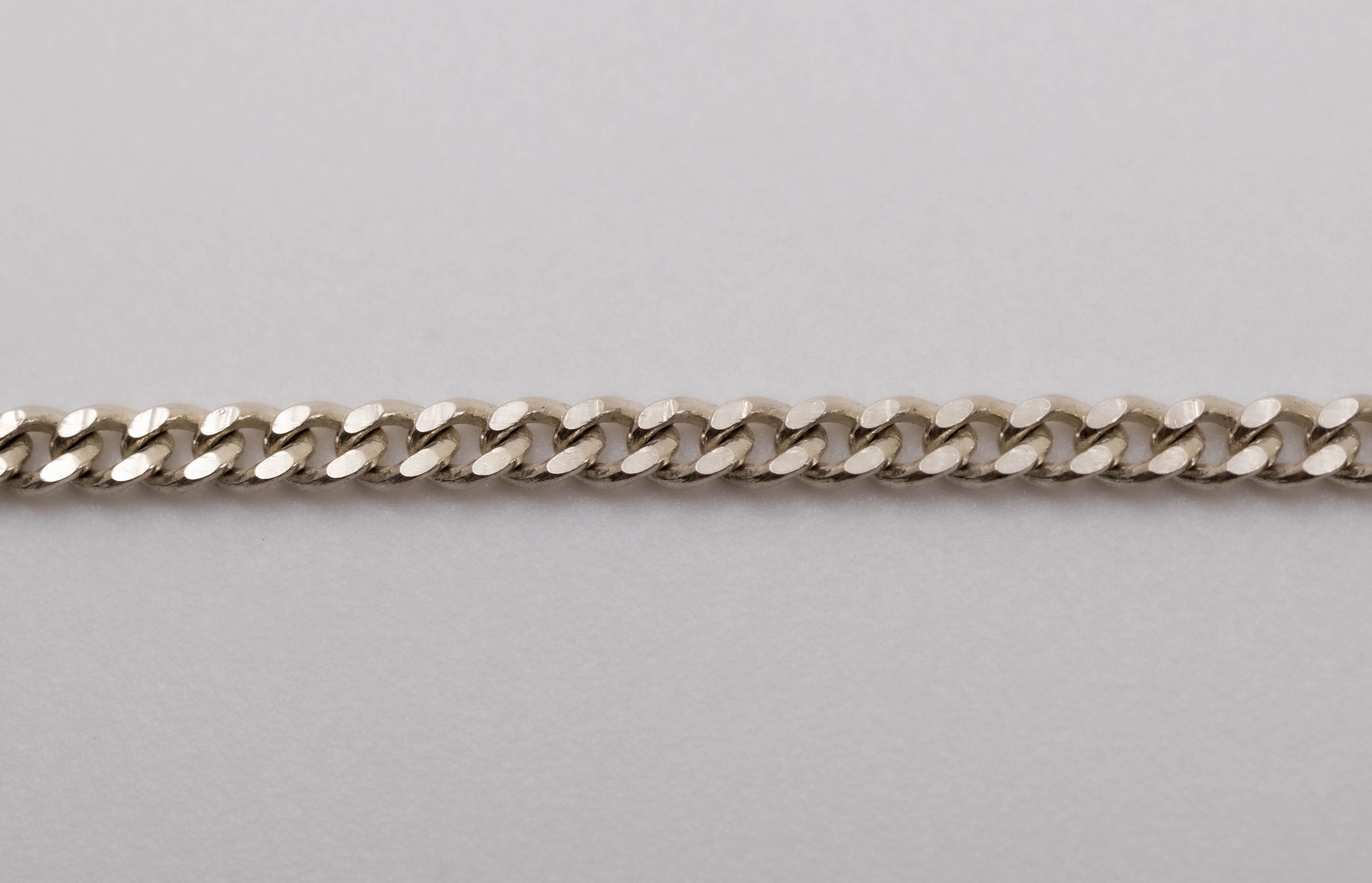 A silver curb-link chain bracelet with the brand name 'CASH' prominently displayed in the center.
