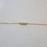 Gold bracelet with one opal and three small diamonds on a white leather surface