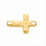 A gold cross-shaped jewelry charm with a hammered texture and two circular holes, shown on a plain white background.