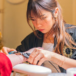 Woman getting a permanent jewelry in a festive setting with Christmas decorations.